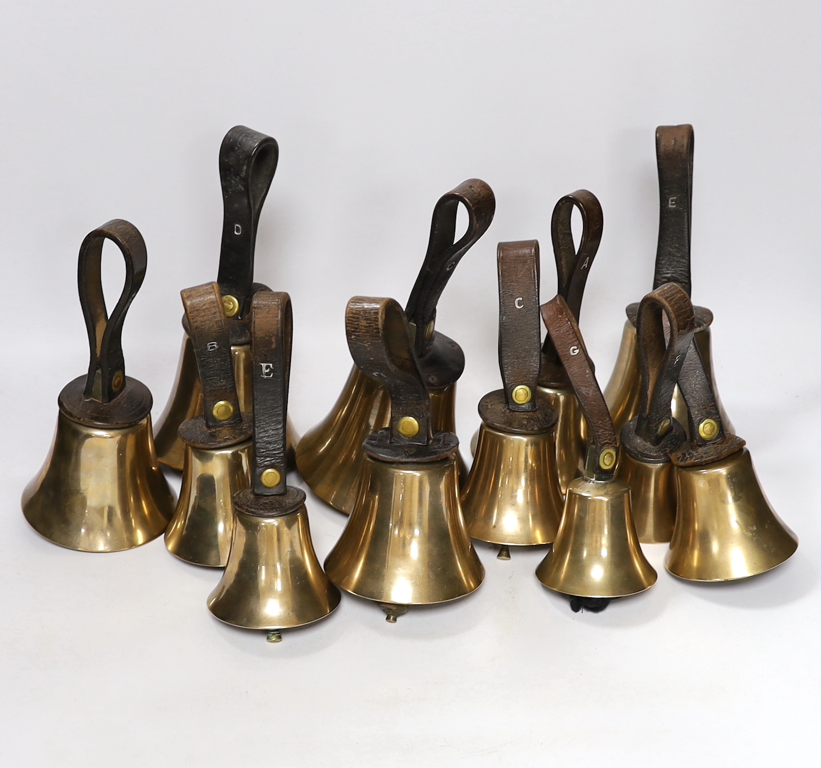 A set of thirty two musical handbells, full chromatic scale, circa 1900, largest 23cm, including leather strap